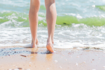 bare feet of a girl walk on the sand on the beach to sea water. summer vacation and travel concept.