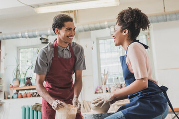 smiling young african american couple sculpting pot on wheel in pottery