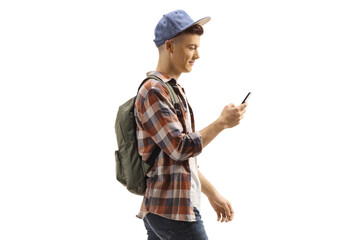 Student with a backpack and cap walking and looking at his mobile phone