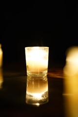 Candle Light Burning Bright with Mirror Reflection on Table in the Black of Night. 
