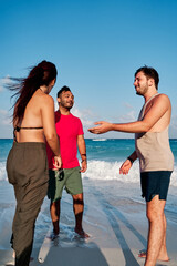 group of three friends, two men and a woman, sharing and talking on the coast of cancun beach, rivera maya, with a turquoise sea in the background