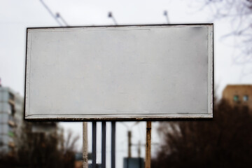 Blank roadside poster in front of blurred city buildings. Blank presentation media mockup template poster