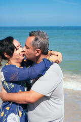 Fototapeta na wymiar Mature latin couple kissing and walking on the beach