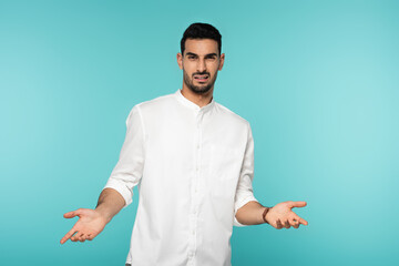 Confused arabian man pointing with hands isolated on blue