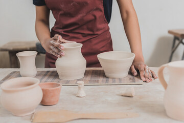 partial view of young african american woman touching clay pot on tray in pottery