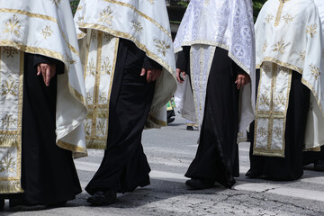 Group of orthodox priests in vestments walk in line crossing the street