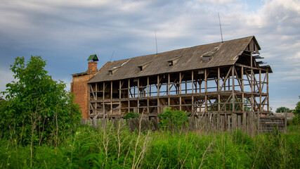Abandoned and ruined old farm overgrown with bushes and trees