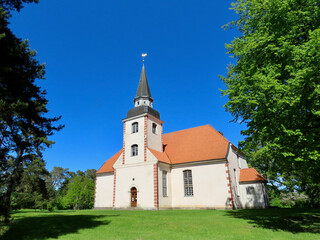 Fototapeta na wymiar Small lutheran church in Liepupe, Latvia, with red roof and white walls. Sunny summer day