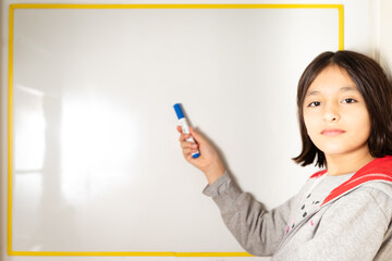 niña escribiendo y pensando en pizarra con fibra en la mano