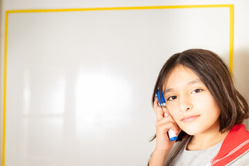 niña escribiendo y pensando en pizarra con fibra en la mano