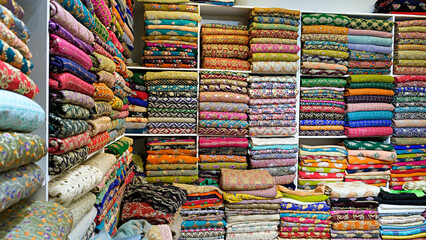 Traditional oriental multicolored clothes stacked in store. Dubai market. Global village pavilion. Selective focus.  Small depth.