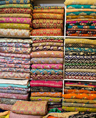 Traditional oriental multicolored clothes stacked in store. Dubai market. Global village pavilion. Selective focus.  Small depth.