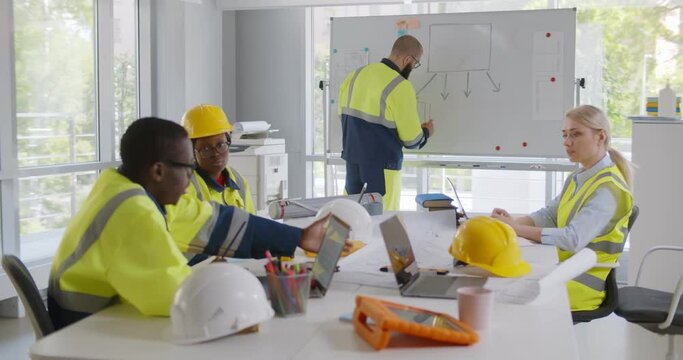 Diverse young architects working on new project with male contractor in office