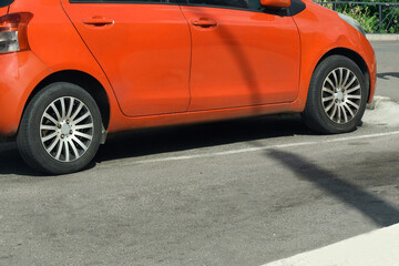 Bottom of orange car with wheels against a background of gray city asphalt. Isolated. Space for text at the bottom.