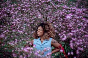 mulher negra de cabelo afro ao redor de flores rosas