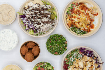 Huge variety of Mediterranean meals on a white table with the bite size falafels on the center of...