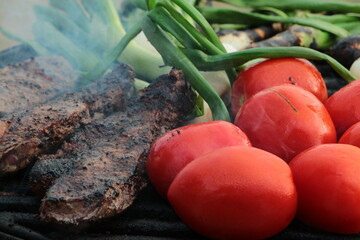 grilling some steak, onions and tomatoes on the grill