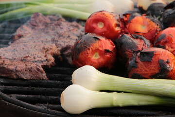 grilling some steak, onions and tomatoes on the grill