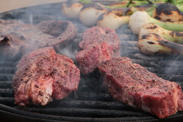 grilling some steak, and onions on the grill
