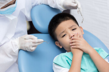 Naklejka premium Dentist examining Asian little boy teeth in clinic. Calm and happy