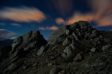 Starry night sky at the mountains long exposure moving clouds