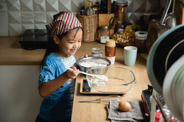 Girl 6-7years mixing flour at kitchen recording video