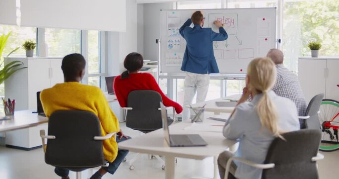 Businessman writing on whiteboard in meeting room