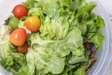 Salad vegetables, tomatoes in a plastic bowl, organic system, healthy food, on a wooden floor.
