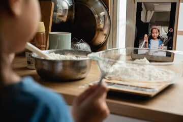 Girl 6-7years mixing flour at kitchen recording video