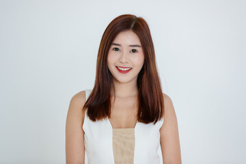 Fototapeta premium Cute pretty smiling joyfully young Asian woman with dark fair hair in casual dress standing and looking friendly at camera with a happy face. Headshot portrait isolated on white background