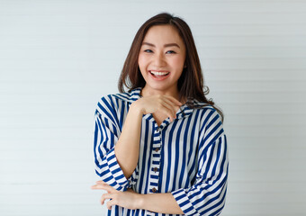 Horizontal close-up portrait shot of attractive smiling Asian woman in casual long sleeve blue and white striped clothes looking at the camera and posing in the studio isolated with white background