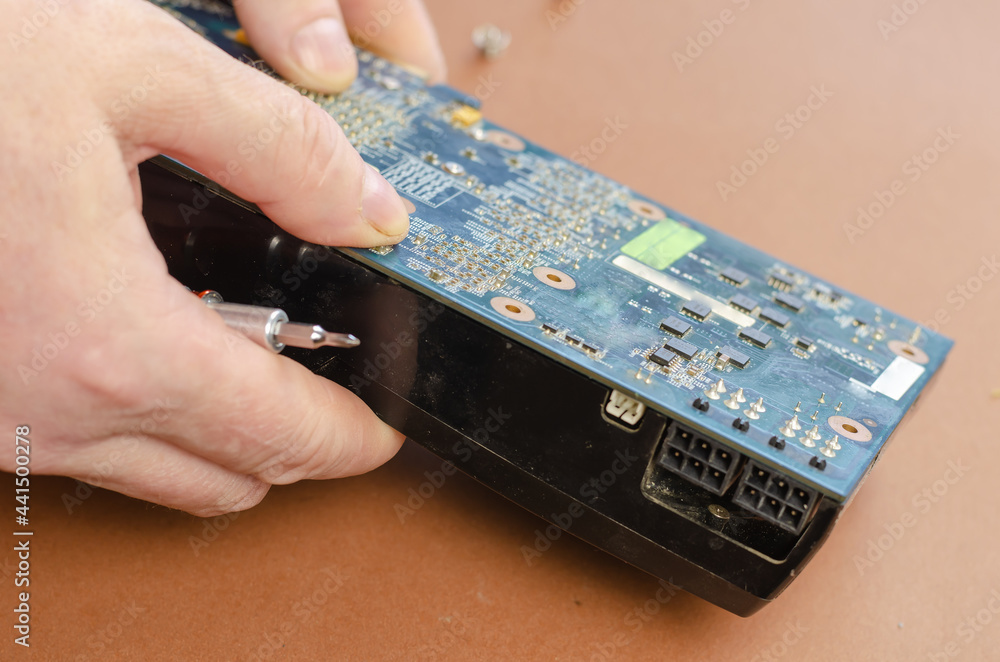 Poster graphics card on a brown background. man disassembles computer components, unscrewing screws. repair