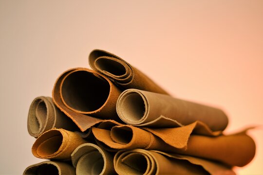  Leather brown assortment. Genuine leather rolls   brown tones on a blurred beige background.Leatherworking.Leather goods material.