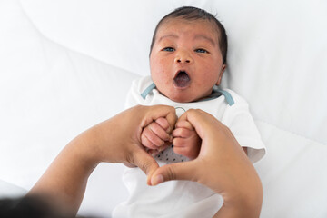 Mother holding hands newborn baby in heart shape. Close-up of newborn baby sleeping on white bed...