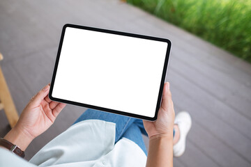Mockup image of a woman holding digital tablet with blank white desktop screen in the outdoors