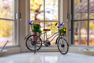 Fototapeta na wymiar A decorative metal forged tricycle with a basket holding plastic flowers on a window of a house, Sunriver, Oregon