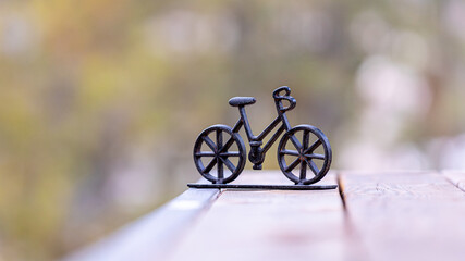 Small isolated decorative metal bike on a wooden deck against a blurry background