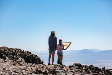 Two girls standing in front of information stand on top of Steens Mountains