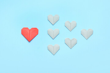 Origami hearts on color background. Concept of uniqueness