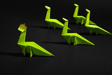 Origami dinosaurs on dark background, closeup. Concept of uniqueness