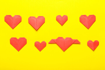 Origami hearts on color background. Concept of uniqueness