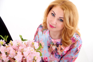 Fototapeta premium Happy beautiful woman with long blond curly hair posing with flowers in studio on white background