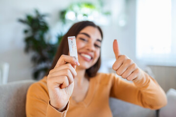 Close-up shot of woman's hand holding a negative test device. Happy young woman showing her...