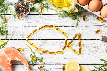 Composition with fish oil pills on light wooden background