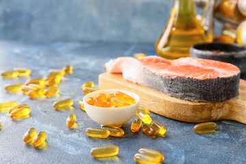 Obraz na płótnie Canvas Raw salmon steak with fish oil pills on color background