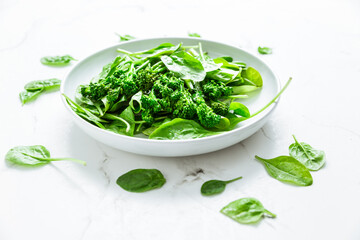 Organic spinach with broccolini (bimi) in bowl on white background