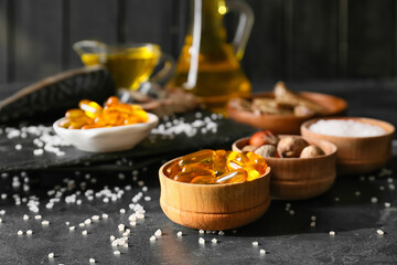 Bowl with fish oil pills on dark background