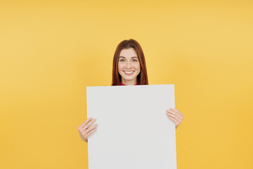 Happy friendly young woman holding a blank white poster