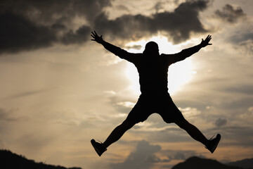 Fototapeta na wymiar Silhouette Man jump on top of the mountain freedom life with sunset.