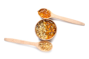Wooden spoons with fish oil pills on white background